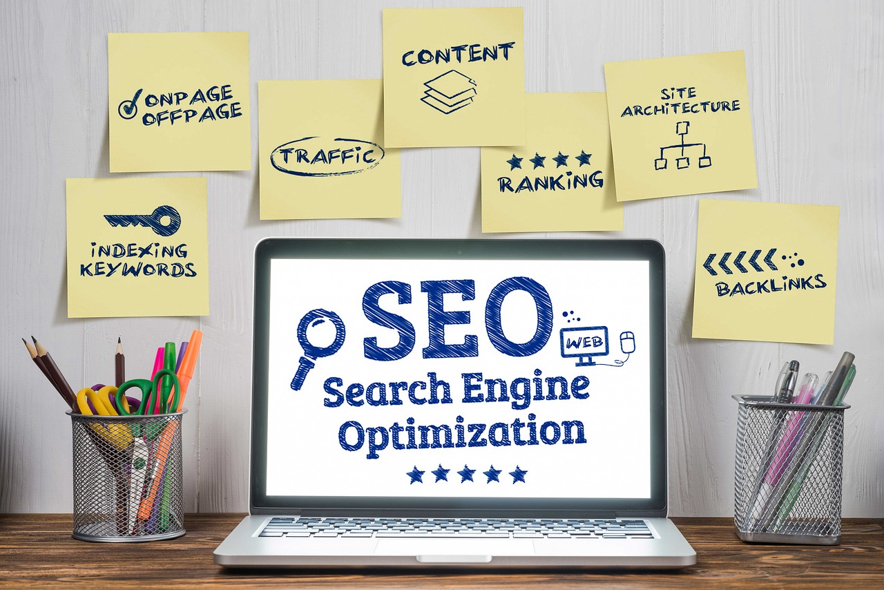 Laptop displaying a search engine optimization graphic surrounded by SEO topic notes