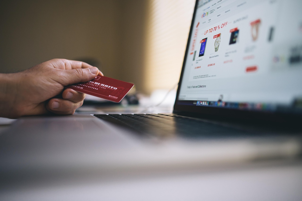 Customer holding a credit card while shopping on a laptop
