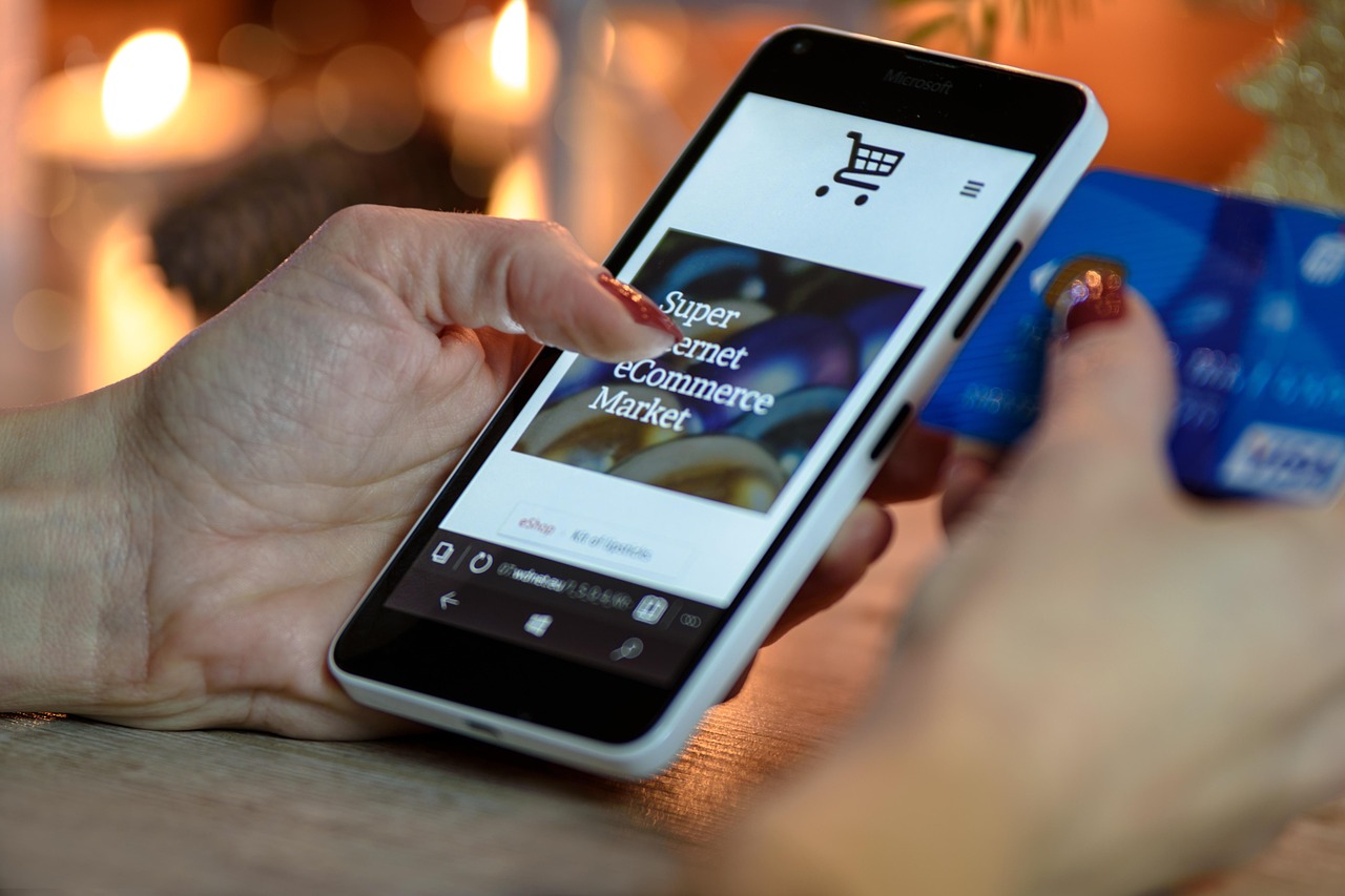 Hand holding a phone with an online store open and a bank card