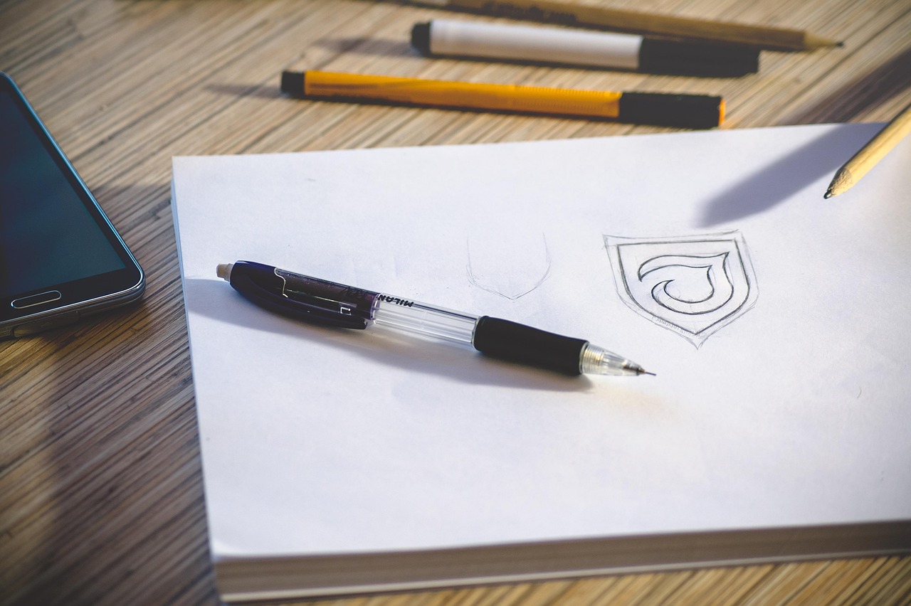 Pen resting on a paper with a hand-drawn logo sketch