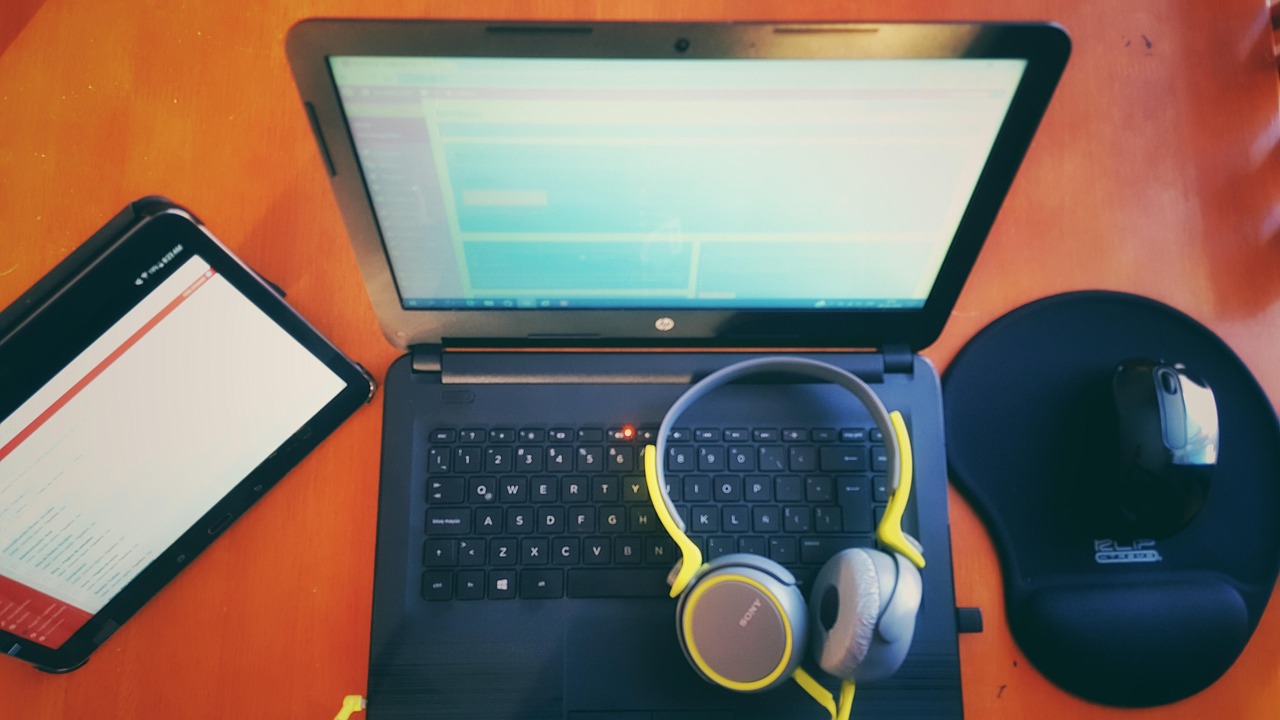 Top-down view of a laptop and tablet on a work desk
