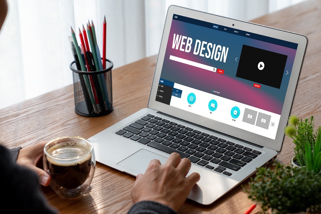 Person working on a laptop with a web design layout on screen