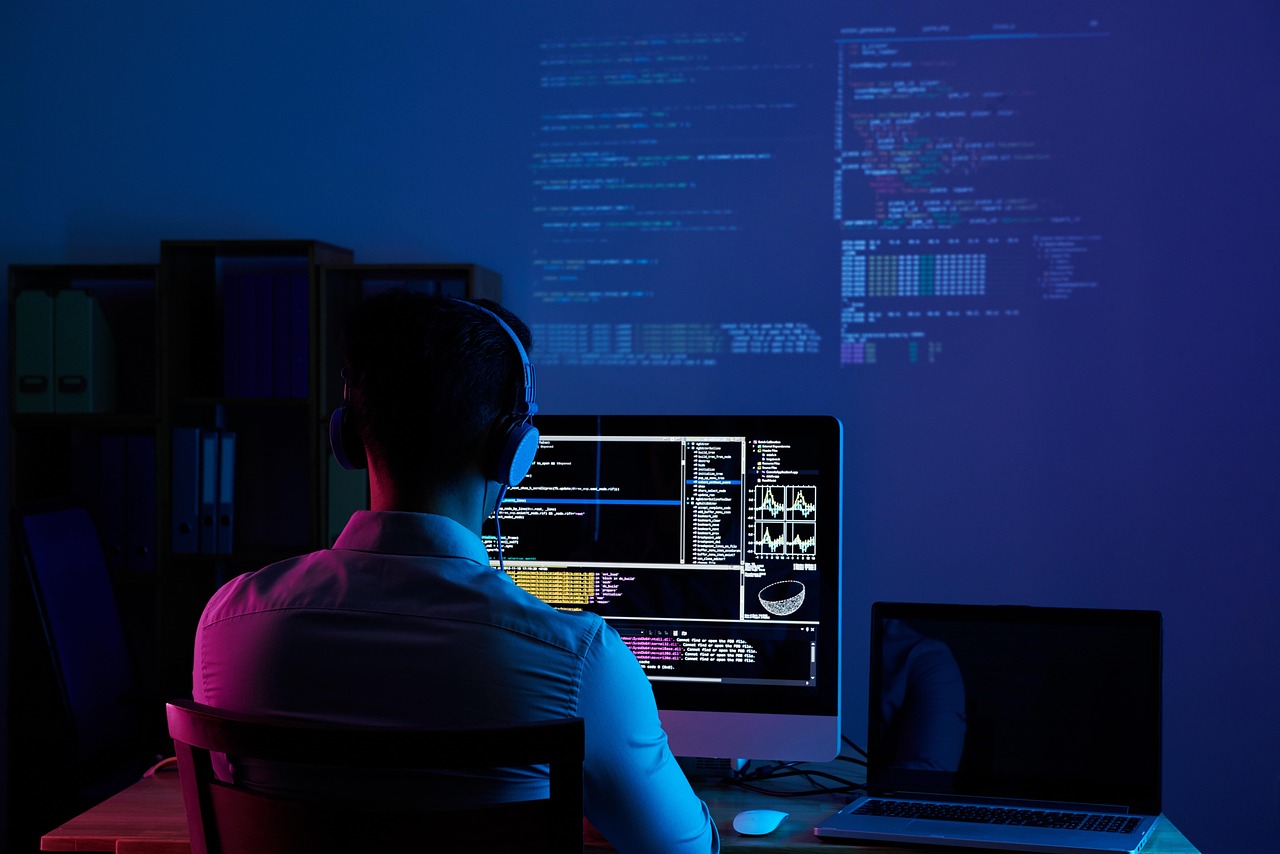 Developer working at a multi-monitor workstation in low light